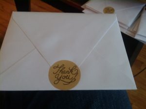 An envelope with a sticker reading "Thank You" in fancy script