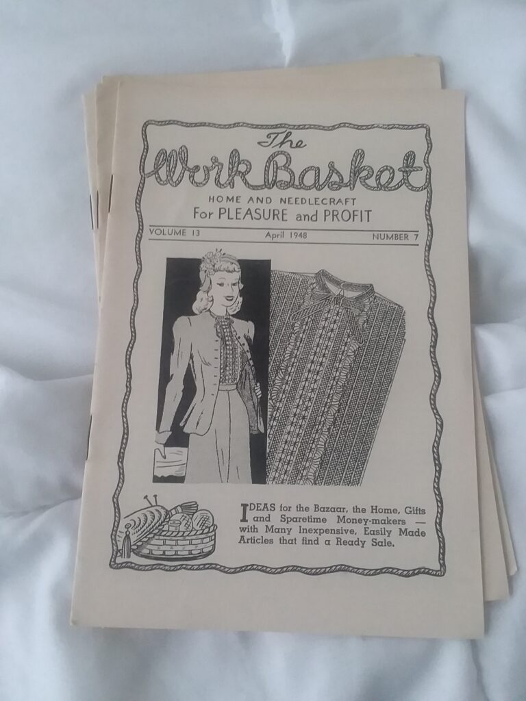 The Workbasket, a small magazine, printed on newsprint. Features a woman and a knitting project on the cover, a line drawing. 